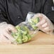 A person in a chef's uniform holding a LK Packaging plastic bag of broccoli.
