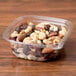 A square plastic deli container filled with nuts and raisins.