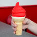 A hand holding an ice cream cone with Phillips cherry shell coating.