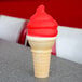 A red and white ice cream cone with a cherry ice cream shell coating.