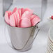 A bucket filled with Classic Pink plastic spoons.
