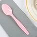 A Creative Converting classic pink plastic spoon on a napkin.