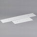Two white plastic strips on a gray metal surface.