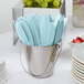 A bucket of blue plastic utensils, including Creative Converting Pastel Blue plastic knives.