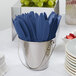 A silver bucket filled with navy blue plastic knives.