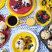 A table set with Fiesta dinnerware including a Sunflower dinner plate with a muffin and strawberries on it.