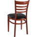 A Lancaster Table & Seating Spartan series wooden chair with a black vinyl seat and ladder back.