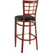 A Lancaster Table & Seating metal window back bar stool with mahogany wood grain finish and black vinyl seat.
