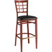 A Lancaster Table & Seating Spartan Series bar stool with a black vinyl seat and mahogany wood grain finish.