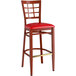 A Lancaster Table & Seating red bar stool with a mahogany wood grain frame and red cushion.
