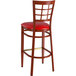 A Lancaster Table & Seating red metal bar stool with a red vinyl seat and mahogany wood grain finish.