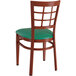 A Lancaster Table & Seating Spartan Series metal window back chair with mahogany wood grain finish and green vinyl seat.