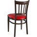 A Lancaster Table & Seating Spartan Series metal chair with a dark walnut wood grain finish and red vinyl seat.