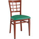 A Lancaster Table & Seating Spartan Series metal chair with a mahogany wood grain finish, green vinyl cushion, and back.
