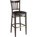 A Lancaster Table & Seating Spartan Series bar stool with a black wood grain frame and black vinyl seat.