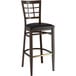 A Lancaster Table & Seating Spartan Series bar stool with a dark walnut wood grain finish and black vinyl seat.