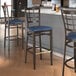 A Lancaster Table & Seating Spartan Series bar stool with a navy vinyl seat and dark walnut wood grain finish.