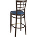 A Lancaster Table & Seating Spartan Series metal bar stool with dark walnut wood grain finish and a navy vinyl seat.