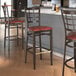 A Lancaster Table & Seating Spartan Series bar stool with a dark walnut wood grain finish and burgundy vinyl seat.