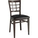 A Lancaster Table & Seating metal window back chair with a dark walnut wood grain finish and black vinyl seat.
