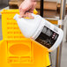 A hand holding a white bottle of 3M Heavy Duty Degreaser.