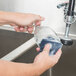 A person cleaning a sink with a 3M Scotch-Brite blue scratchless power pad.