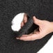 A hand holding a black 3M 7200 stripping pad.