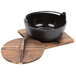 A black Thunder Group cast iron noodle bowl on a wooden tray.