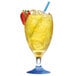 A glass of yellow liquid with a straw and a strawberry sitting next to a Manitowoc IDT1500W water cooled ice machine.