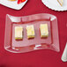 A Fineline clear plastic dessert plate with a slice of cake on a red tablecloth.