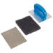 A 3M Scotch-Brite griddle pad holder with a blue handle on a metal plate with a black sponge pad.