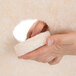 A hand holding a white 3M burnishing pad.