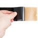 A hand holding a piece of black and brown 3M Safety-Walk tape.