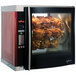 A large Alto-Shaam rotisserie oven with cooked chicken on 7 spits.