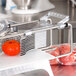 A close-up of a red Vollrath pusher head slicing a tomato.