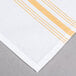 A white and gold striped Snap Drape Softweave cloth napkin.