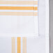 A white and gold striped cloth napkin with a close up of the fabric.
