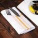 A gold Softweave Bistro striped cloth napkin with a fork on a plate of mussels and a lemon.