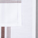 A white cloth napkin with a brown stripe down the middle.