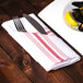 A plate of mussels with a fork and lemon on a red and white striped Snap Drape Softweave cloth napkin.