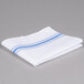 A folded white cloth napkin with blue stripes.