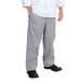 A person wearing Chef Revival houndstooth baggy cook pants and a white shirt with hands in pockets.