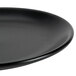 A close-up of a Hall China Foundry black coupe plate with a black rim.
