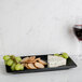 A Hall China black rectangular platter with cheese, bread, and grapes on a table.
