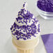 An ice cream cone with purple sprinkles.