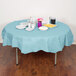 A table with a pastel blue Creative Converting tablecloth, plates, and cups.