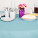 A table with a pastel blue table cover and plates, utensils, and cups on it.