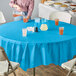 A table with a turquoise blue OctyRound plastic table cover and glasses of liquid.