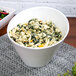A 10 Strawberry Street white porcelain tall slant bowl filled with pasta, spinach, and cheese.
