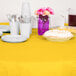 A table with a School Bus Yellow OctyRound table cover with plates and cups on it.
